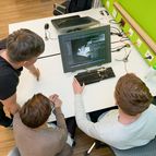 Drei Studierende arbeiten gemeinsam vor dem Monitor an einer Designaufgabe 