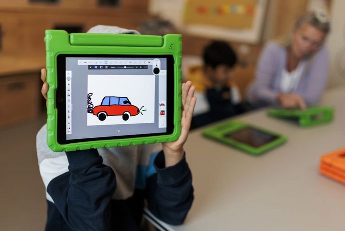 Kind hält ein Tablet auf dem ein Auto gezeichnet wurde