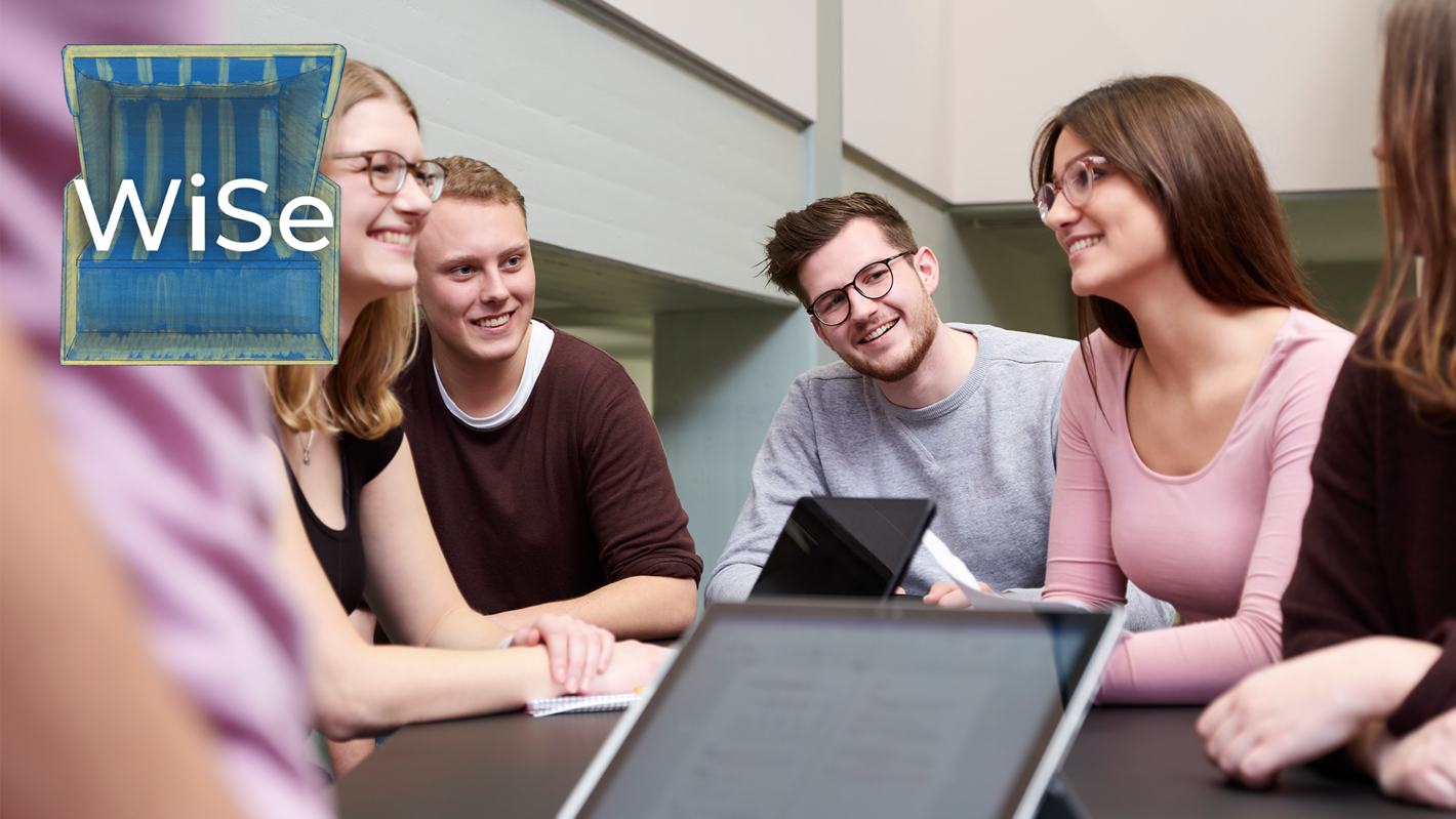 Eine Gruppe von Studierenden sitzt um einen Tische herum und unterhält sich angeregt.